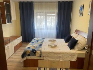 a bedroom with a bed with blue curtains and a window at Bavaria Apartament in Mangalia