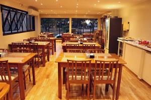 an empty restaurant with wooden tables and chairs at Klinn Hotel in Tanabi