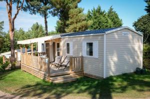 un pequeño cobertizo blanco con 2 sillas en una terraza en Mobil Home XXL 4 chambres - Camping Le Clos Cacheleux, en Miannay