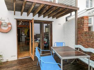 a patio with a wooden table and blue chairs at Cowes View Cottage in Fareham