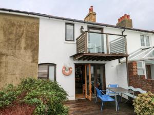 a white house with a blue chair and a table at Cowes View Cottage in Fareham