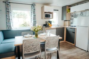 een keuken en eetkamer met een tafel en stoelen bij Mobil Home XXL 4 chambres - Camping Le Clos Cacheleux in Miannay