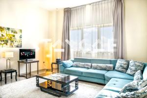 a living room with a blue couch in front of a window at Staycae Holiday Homes - Suburbia, Jebel Ali in Dubai