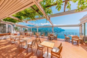 ラヴェッロにあるガーデン ホテルのテーブルと椅子が備わり、海の景色を望むレストラン