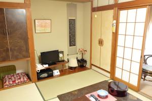 un salon avec une télévision et une chambre avec dans l'établissement Hinodeya, à Itō