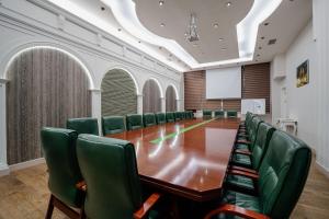 Hills Resort Hotel في يريفان: قاعة اجتماعات مع طاولة طويلة وكراسي خضراء