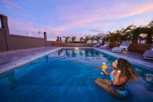 a woman sitting on a rock in a swimming pool at LES VILLAS LOURYA MARIE-GALANTE in Grand-Bourg