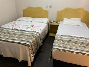 two beds sitting next to each other in a room at Klinn Hotel in Tanabi