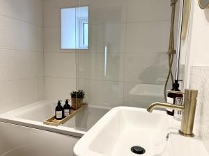 a bathroom with a sink and a tub with two bottles at Trevose in Wrexham