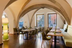 een restaurant met tafels, stoelen en ramen bij Altstadthotel Arch in Regensburg