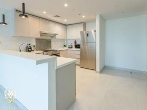 uma cozinha com armários brancos e um frigorífico de aço inoxidável em Luxury 1BR Apt with Unobstructed Dubai Frame View em Dubai