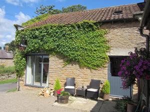 uma casa de pedra com duas cadeiras e hera em Blacksmith’s Barn - Cosy, Chilled & Dog Friendly. em Wykeham