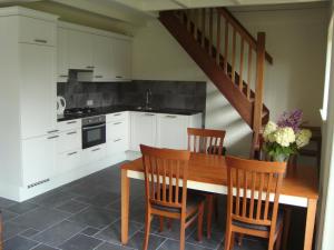 una cocina con armarios blancos y una mesa y sillas de madera. en Vakantiehuis "Aan de Zandweg" en Roderesch