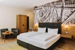 a bedroom with a bed with a painting on the wall at Altstadthotel Arch in Regensburg