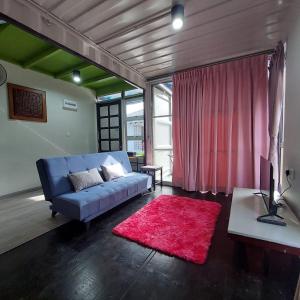 a living room with a blue couch and a red rug at Laman Sakinah Merlimau in Merlimau