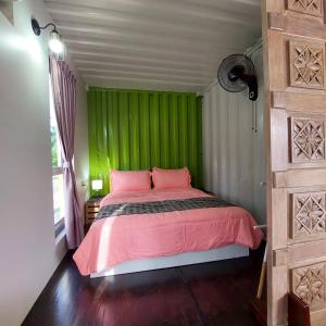 um quarto verde com uma cama rosa e uma janela em Laman Sakinah Merlimau em Merlimau