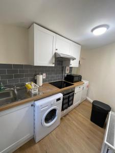a kitchen with white cabinets and a washer at Riverside Cottage in Kent