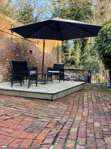 un patio con 2 sillas y una sombrilla en Riverside Cottage en Kent