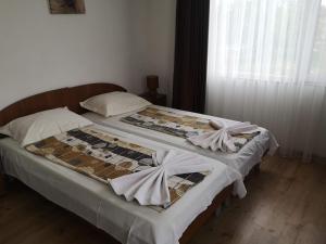 two beds in a bedroom with white sheets at Miraj-MD in Primorsko