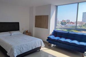 1 dormitorio con sofá azul y ventana grande en Estudio para 3, Norte de Barranquilla, en Barranquilla