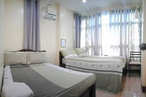1 dormitorio con 2 camas y ventana con silla en DJL Summer House - Bantayan Island, en Patao