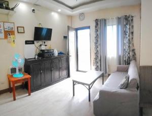 ein Wohnzimmer mit einem Sofa und einem TV in der Unterkunft DJL Summer House - Bantayan Island in Patao
