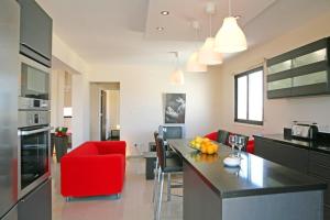 a kitchen and living room with red chairs and a counter at Artemis Executive Suite in Larnaca