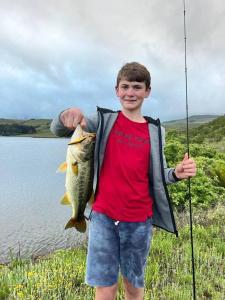a young boy holding a fish in front of a lake at Meshlynn Farm House in Thendele