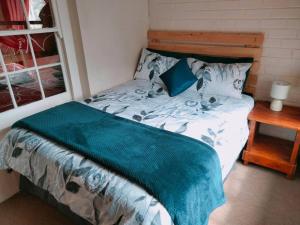 uma cama com um cobertor azul num quarto em Meshlynn Farm House em Thendele