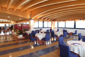 una sala da pranzo con tavoli bianchi e sedie blu di Hotel Yria a Vieste