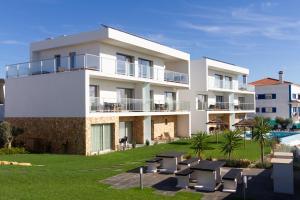 a large white building with a pool in front of it at Ericeira Surf Apartments in Ericeira