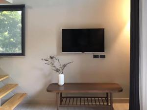 uma sala de estar com uma mesa e uma televisão na parede em Onhill Village em Pong Talong