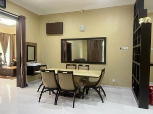 a dining room with a table and chairs and a mirror at Homestay Rohmat in Kota Bharu