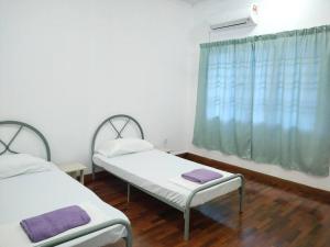 two beds in a room with a window at Sapporo Homestay in Skudai