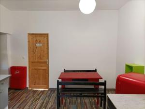 a room with a red table and a door at T2 centre village "Chez Clothilde" in Remoulins