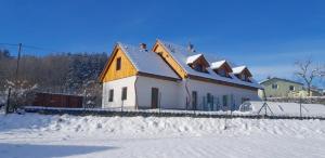 een huis met sneeuw op de grond ervoor bij apartmán pod Ještědem in Světlá pod Ještědem