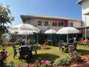 a group of tables and chairs with umbrellas in a yard at Hotel Soham Retreat in Mahabaleshwar