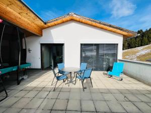 patio z niebieskimi krzesłami i stołem na domu w obiekcie 3 bedroom condo in front of Obersaxen ski resort w mieście Obersaxen