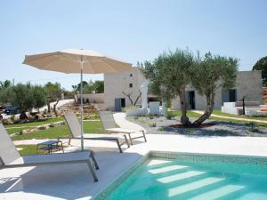 uma piscina com cadeiras e um guarda-sol ao lado de uma casa em Charming holiday home with annex and pool near Cisternino em Cisternino