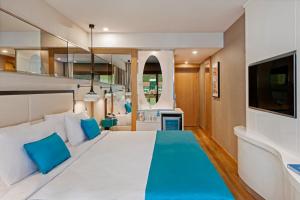 a bedroom with a large white bed with blue pillows at Elite World Marmaris - Adult Only in Marmaris