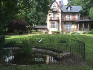 une vieille maison avec un étang en face de celle-ci dans l'établissement Villa du Châtelet, à Choisy-au-Bac