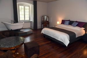 a bedroom with a large bed and a bath tub at Auberge de Bellelay in Bellelay