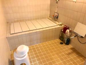 a bathroom with a toilet and a tiled floor at Kappo Ryokan Uoichi in Shimada