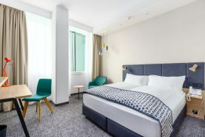 a hotel room with a bed and a desk and chairs at Holiday Inn - Vienna - South, an IHG Hotel in Vienna