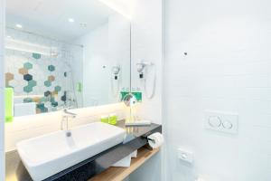 bagno bianco con lavandino e specchio di Holiday Inn - Vienna - South, an IHG Hotel a Vienna