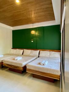 2 Betten in einem Zimmer mit grüner Wand in der Unterkunft TEZA Resort in Bantayan