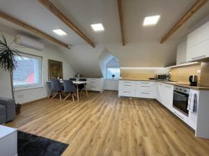 a large kitchen with white cabinets and a table at Apartmán Světla in Pardubice