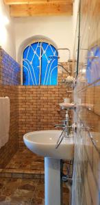 baño con lavabo y ventana azul en HabuHeritageHomeStayInLuxor, en Al Aqālitah