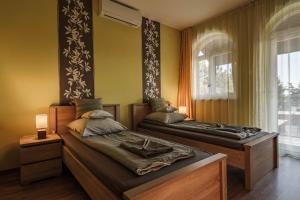 a bedroom with two beds and a window at Garden Vendégház Makó in Makó