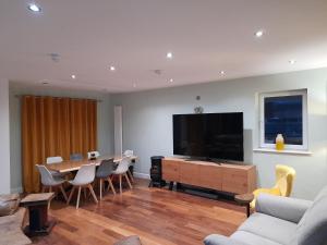 sala de estar con mesa y TV de pantalla plana en Coastal Millennium Apartment, en Llanelli